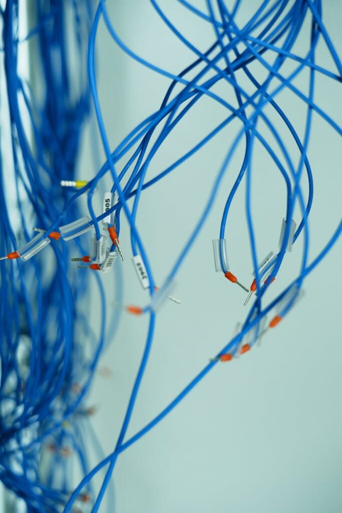 Close-up of tangled blue wires with connectors on a white background, emphasizing connection.