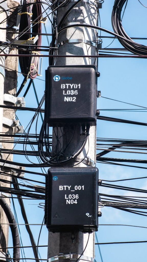 Close-up of telecommunication boxes on a utility pole with tangled cables.